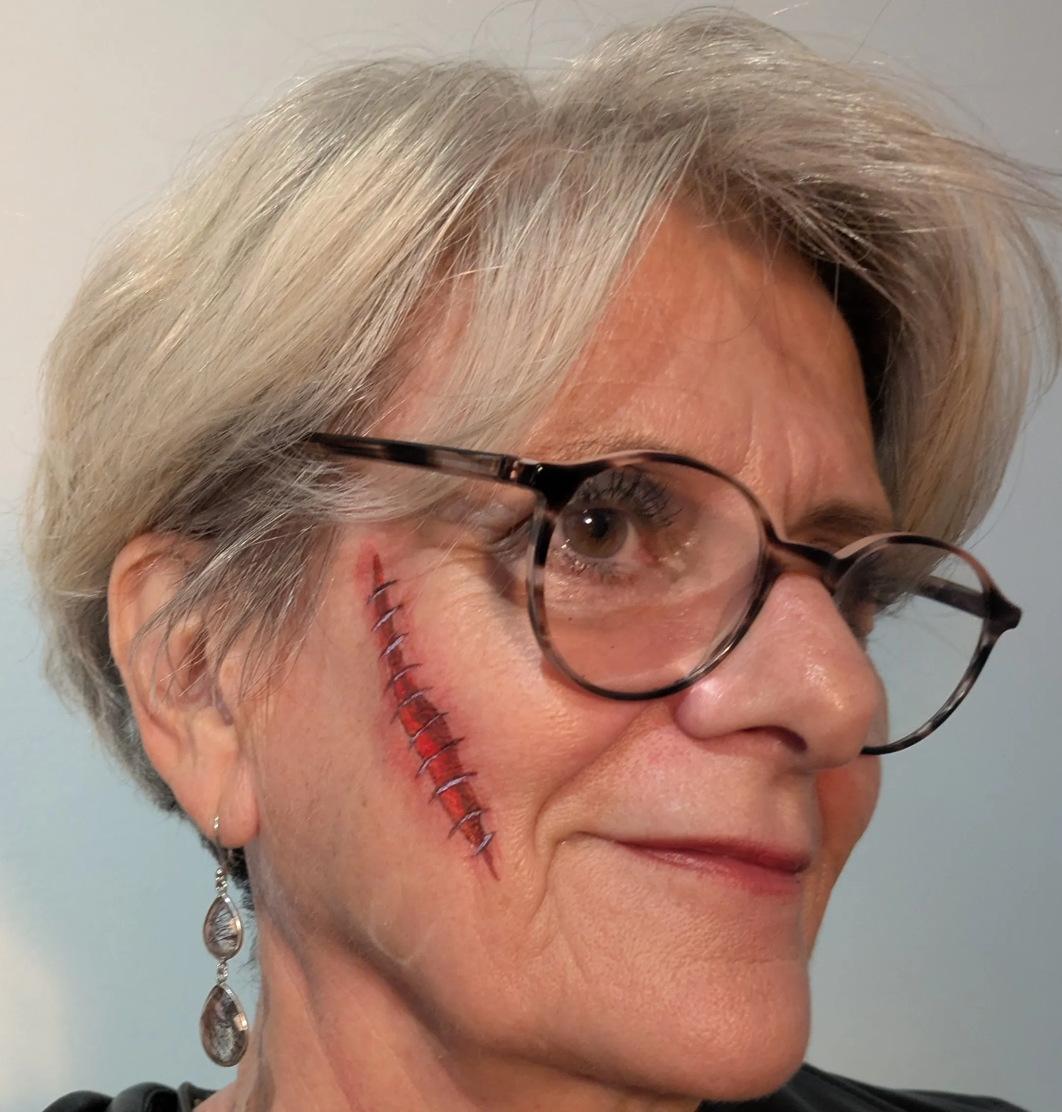 Maquillage artistique Halloween avec fausse plaie, sang et points de suture